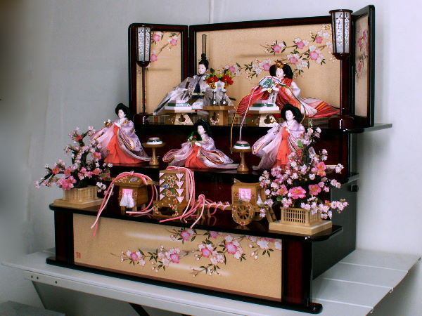 春らしくほんのり赤い桜色の衣装を着せつけた初々しいひな人形三段飾り