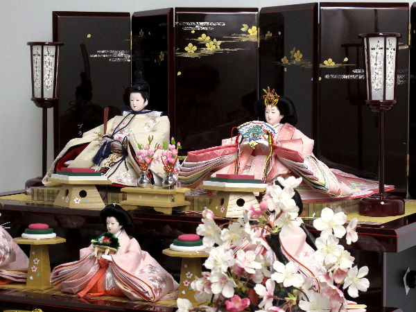 桜色のおひなさまを深い茶塗りの落ち着いた飾り台でまとめた豪華な雛人形です。