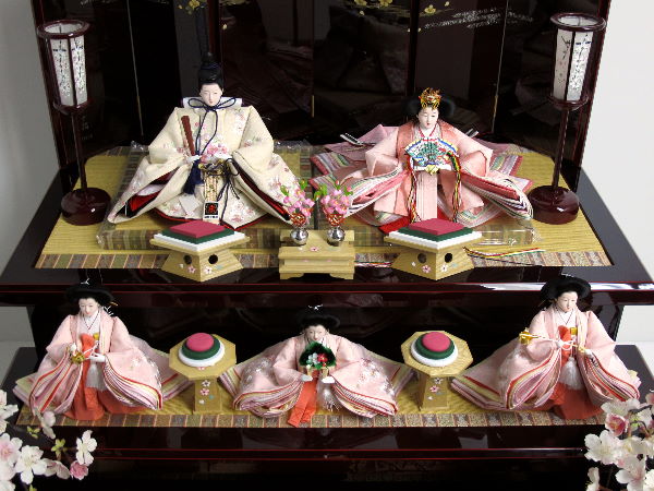 桜色のおひなさまを深い茶塗りの落ち着いた飾り台でまとめた豪華な雛人形です。