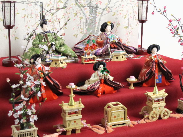 平安貴族の愛用した有職文様、鶴の丸を正絹衣装に織り込み着せ付けたお雛さまを三段飾りにしました。紅白の梅の木を左右に飾りました。オプションで毛氈・屏風がアレンジできます。