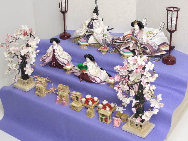落ち着いた紫グラデーションに桜刺繍のアクセントが入った渋めの雛人形を三段飾りにしました。嫁入り道具がすべて揃った飾りです。オプションで毛氈・屏風がアレンジできます。