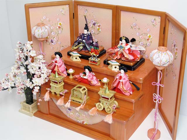 赤の女雛、濃い紫の男雛、ピンクの官女を三段に飾り、大桜を脇に置いた豪華な飾りです。桜のある御殿で宴をしているような素敵な雰囲気になりました。