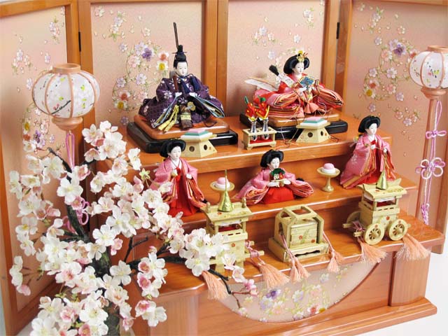 赤の女雛、濃い紫の男雛、ピンクの官女を三段に飾り、大桜を脇に置いた豪華な飾りです。桜のある御殿で宴をしているような素敵な雰囲気になりました。