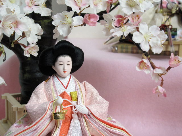 桜色のおひなさまを毛氈を敷いた二段飾りにしました。桐箱に収納します。桜の木が美しい創作雛人形です。