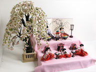 大きな桜を脇に飾ったピンク衣装雛を収納式の二段飾りにしました。