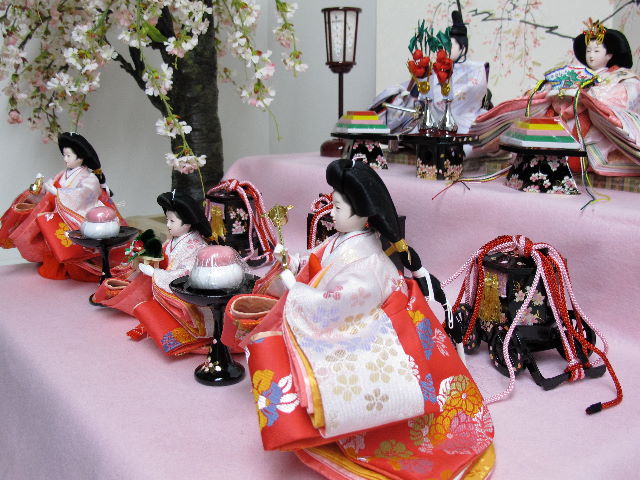 大きな桜を脇に飾ったピンク衣装雛を収納式の二段飾りにしました。