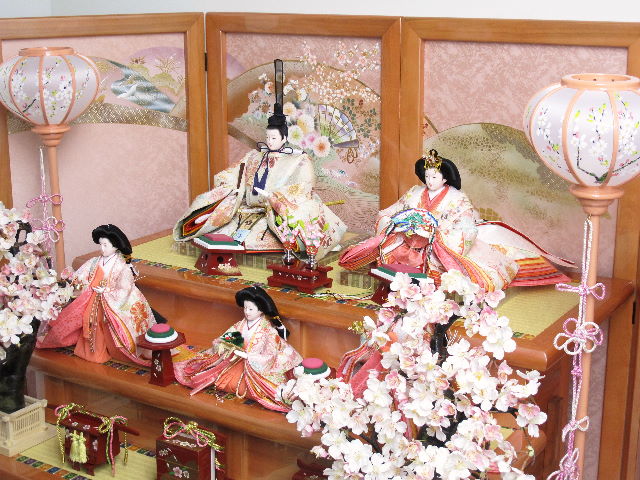 おとなしいピンクの人形をピンクの三段台で飾り、大きな桜を両脇に配した間口135cmの豪華でおしゃれな雛飾りです。