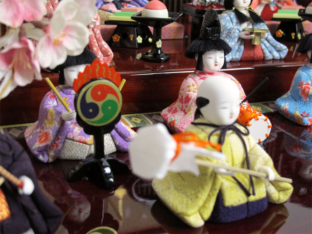 ちいさくてかわいい木目込み人形の十五人揃いです。桜柄の友禅衣装雛を重厚な春慶塗の収納式六角台に所狭しと並べます。