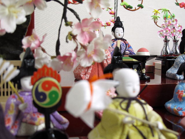 ちいさくてかわいい木目込み人形の十五人揃いです。桜柄の友禅衣装雛をため塗りの二段飾り台に所狭しと並べます。