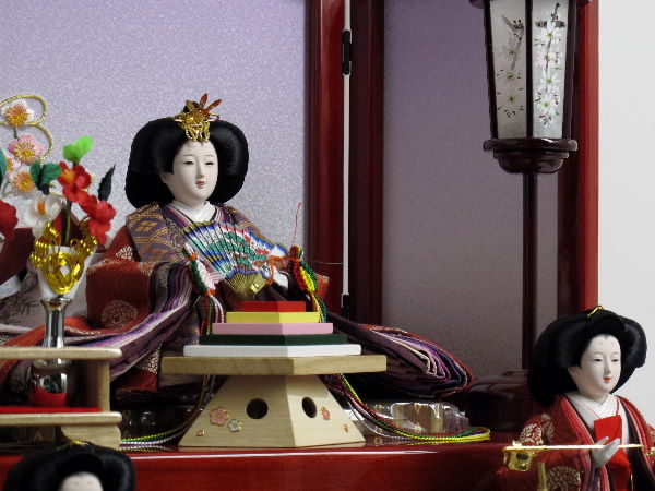 丸の鶴の衣装を着せ付けた有職文様雛をにぎやかに官女やお道具と一緒に赤い三段台に飾ります。