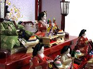 丸の鶴の衣装を着せ付けた有職文様雛をにぎやかに官女やお道具と一緒に赤い三段台に飾ります。