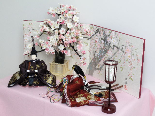 春の息吹が伝わる手描き金泥衣装を着せ付けた品格のある雛人形を桜屏風の前に大きな桜の木と共に優雅に飾りました。桐箱に収める便利な収納タイプです。