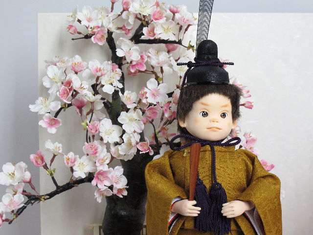 かわいらしい表情が特徴の立ち雛をを桜屏風の前に大きな桜の木と共に優雅に飾りました。桐箱に収める便利な収納タイプです。