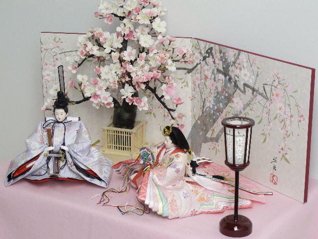 淡いピンクと紫のお雛様を桜屏風の前に大きな桜の木と共に優雅に飾りました。桐箱に収める便利な収納タイプです。