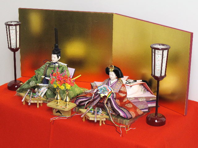伝統的な有職文様に身を包んだ高貴な雛人形を巻物と金屏風で並べる収納