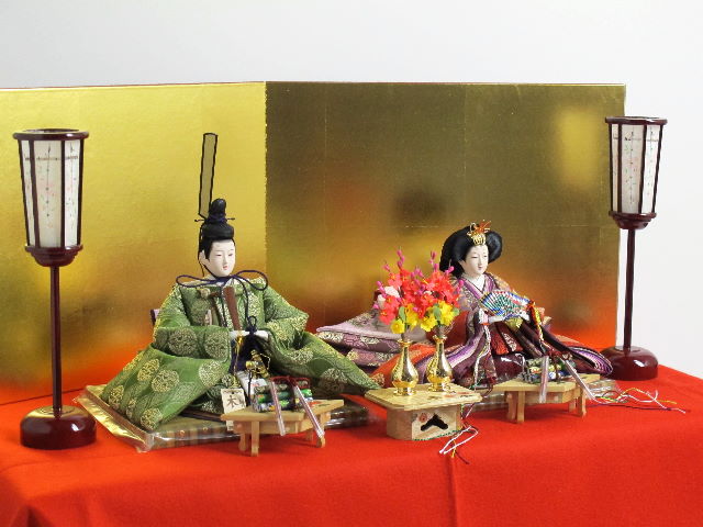 伝統的な有職文様に身を包んだ高貴な雛人形を巻物と金屏風で並べる収納
