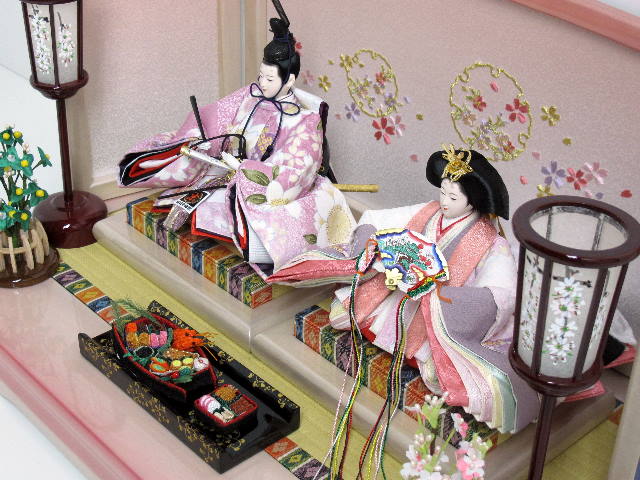 桃色の雛人形をピンクぼかしのかわいい台と屏風に飾りました。ちりめんのおせち料理も特徴です。