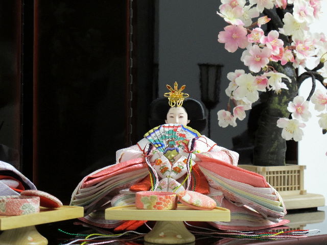 淡い桜色の女雛と藤色の男雛をシンプルに桜の木と飾りました。重厚な溜塗り台を使用した創作親王です。